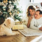 couple sitting by a christmas tree with their dog