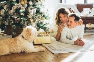 couple sitting by a christmas tree with their dog