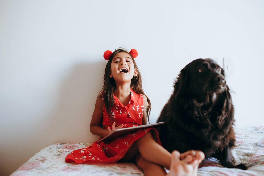 kid sitting on a bed with dog